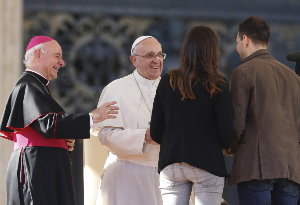 Pope Francis greets Miriam and Marco, an engaged couple who spoke during an audience for engaged couples in St. Peter's Square at the Vatican February 14, Valentine's Day. At left is Archbishop Vincenzo Paglia, president of the Pontifical Council for the Family. 
