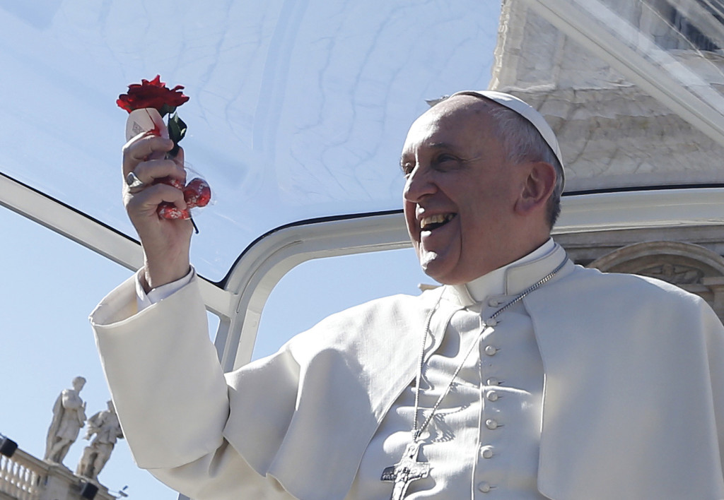 Pope Francis holds a rose and chocolates thrown by a person in the crowd as he arrives for an audience for engaged couples in St. Peter's Square at the Vatican Feb. 14, Valentine’s Day. (Feb. 14, 2014). 
