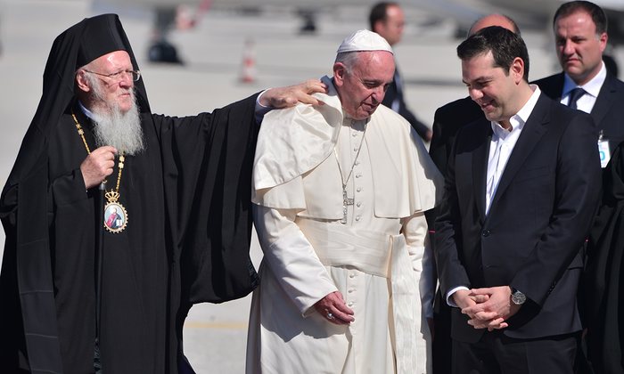 Greek Orthodox Ecumenical Patriarch Bartholomew adjusts Francis’s collar, while Greek President Tsipras speaks to the Pope on the other side. Photograph: Louisa Gouliamaki/AFP/Getty Images