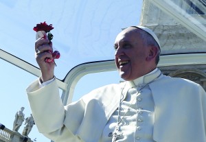 Pope Francis holds a rose and chocolates thrown by a person in the crowd as he arrives for an audience for engaged couples in St. Peter's Square at the Vatican Feb. 14, Valentine's Day. (CNS photo/Paul Haring) (Feb. 14, 2014) See POPE-VALENTINE Feb. 14, 2014.
