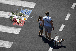 A woman and a child stand near a makeshift memorial placed on the road during a minute of silence on the third day of national mourning to pay tribute to victims of the truck attack along the Promenade des Anglais on Bastille Day that killed scores and injured as many in Nice, France, July 18, 2016. REUTERS/Eric Gaillard