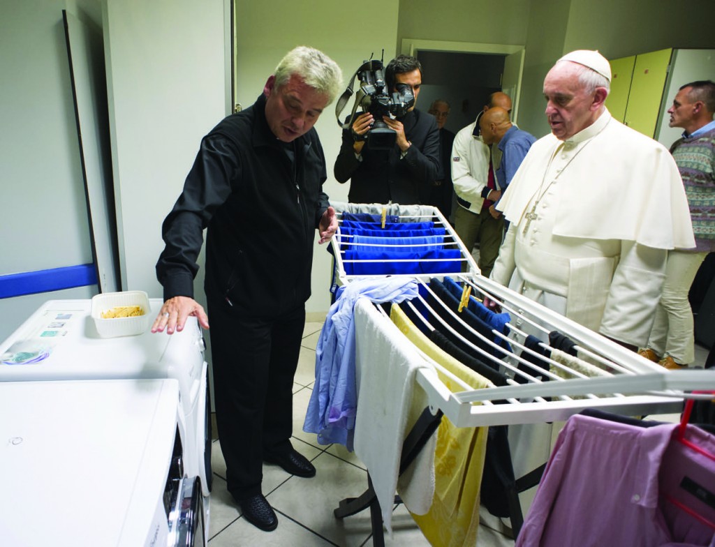 Pope Francis listens as Archbishop Konrad Krajewski, the papal almoner, offers an explanation during the pope's visit to a new homeless shelter for men in Rome Oct. 15. Housed in a Jesuit-owned building, the shelter was created by and is run with funds from the papal almoner. (CNS photo/L'Osservatore Romano, handout) See SHELTER-ROME Oct. 13, 2015.